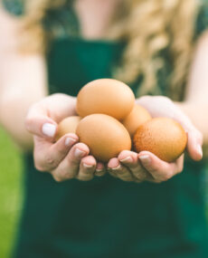 Young,Woman,Showing,Eggs,Standing,On,A,Lawn